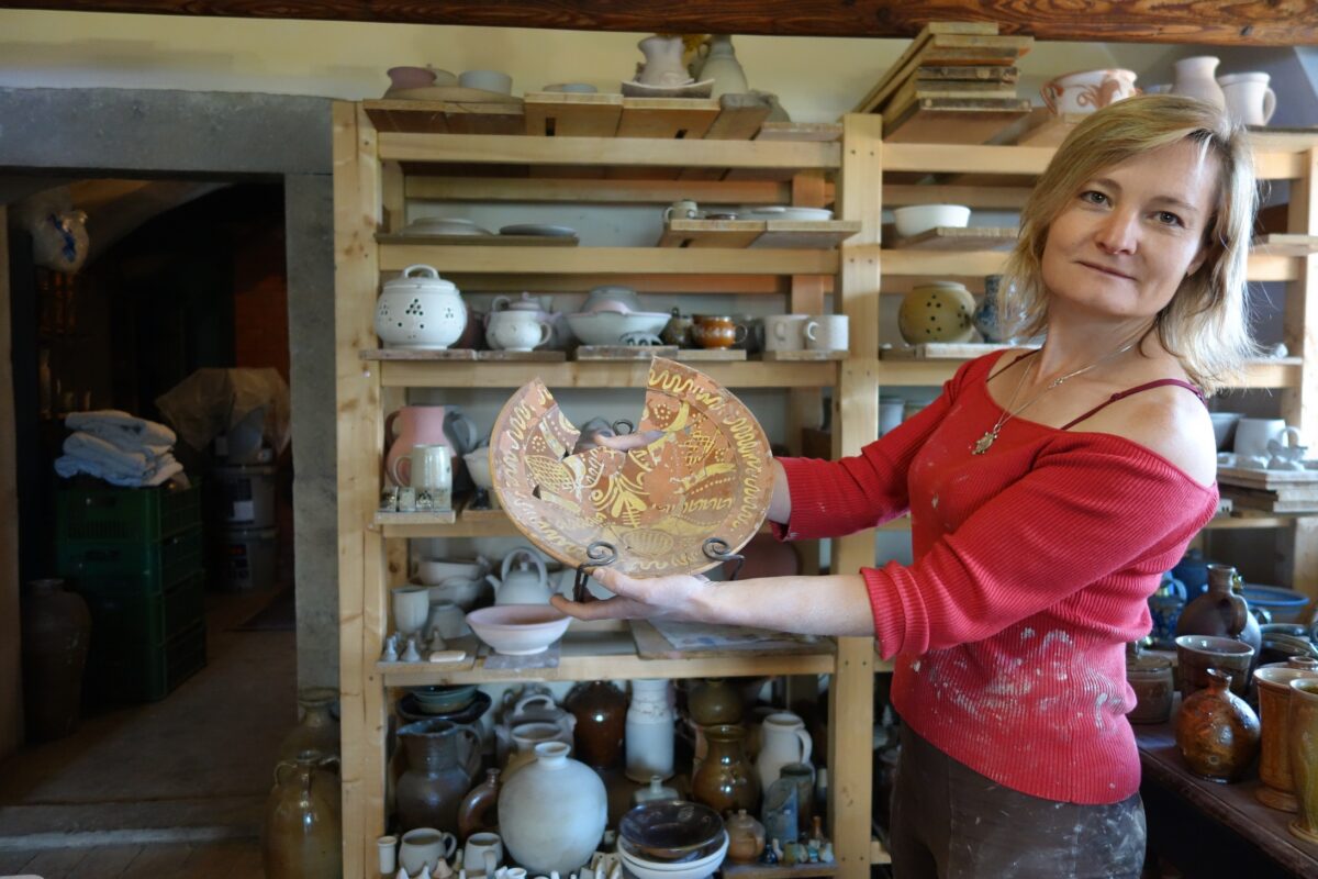 Magdalena Brožová zeigt einen in Engobe-Keramik gefertigten historischen Teller aus Lewiner Geschirr. Die Keramikerin hat die jahrhundertelange Tradition neu belebt. Foto: Steffen Neumann