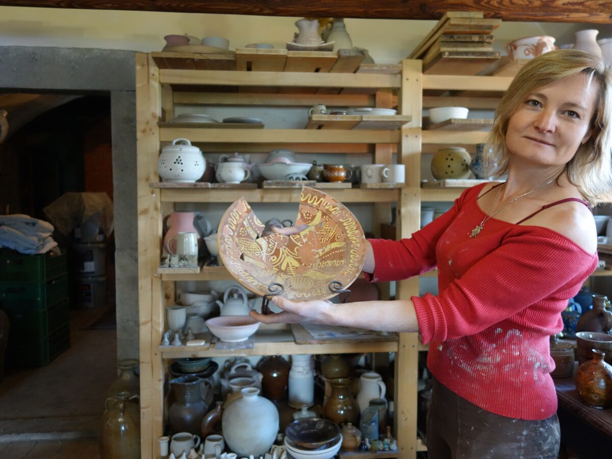 Magdalena Brožová zeigt einen in Engobe-Keramik gefertigten historischen Teller aus Lewiner Geschirr. Die Keramikerin hat die jahrhundertelange Tradition neu belebt. Foto: Steffen Neumann
