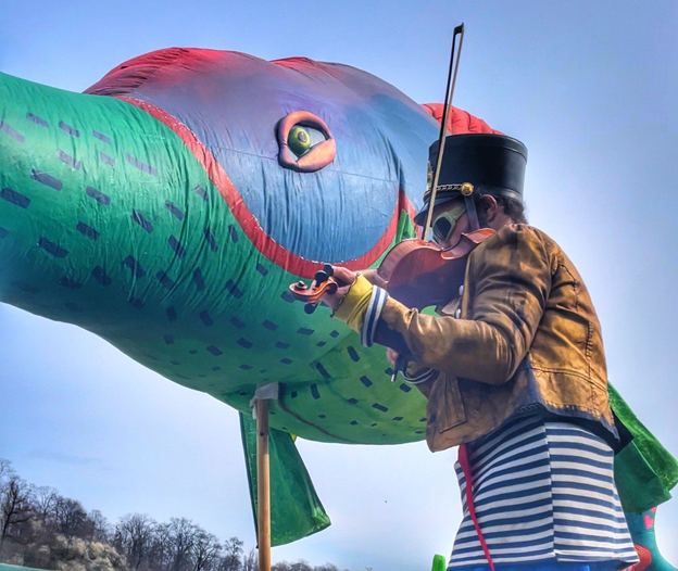 Großer aufblasbarer Fisch mit einem Matrosen, der Geige spielt. Credit: Kseniia Pulargina