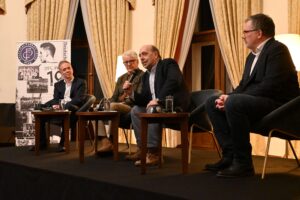 Martin Holler, Marcel Reif, Tomáš Kraus und Filip Bláha sitzen nebeneinander auf Stühlen im Kuppelsaal der deutschen Botschaft in Prag.