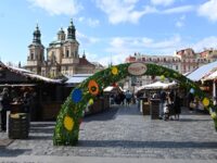 Osterdekoration und Marktstände auf dem Ostermarkt am Altstädter Ring in Prag mit der St.-Nikolaus-Kirche im Hintergrund.
