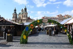 Osterdekoration und Marktstände auf dem Ostermarkt am Altstädter Ring in Prag mit der St.-Nikolaus-Kirche im Hintergrund.