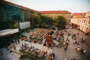 Im Innenhof der Kasárna Karlín sitzen Menschen auf Bänken.