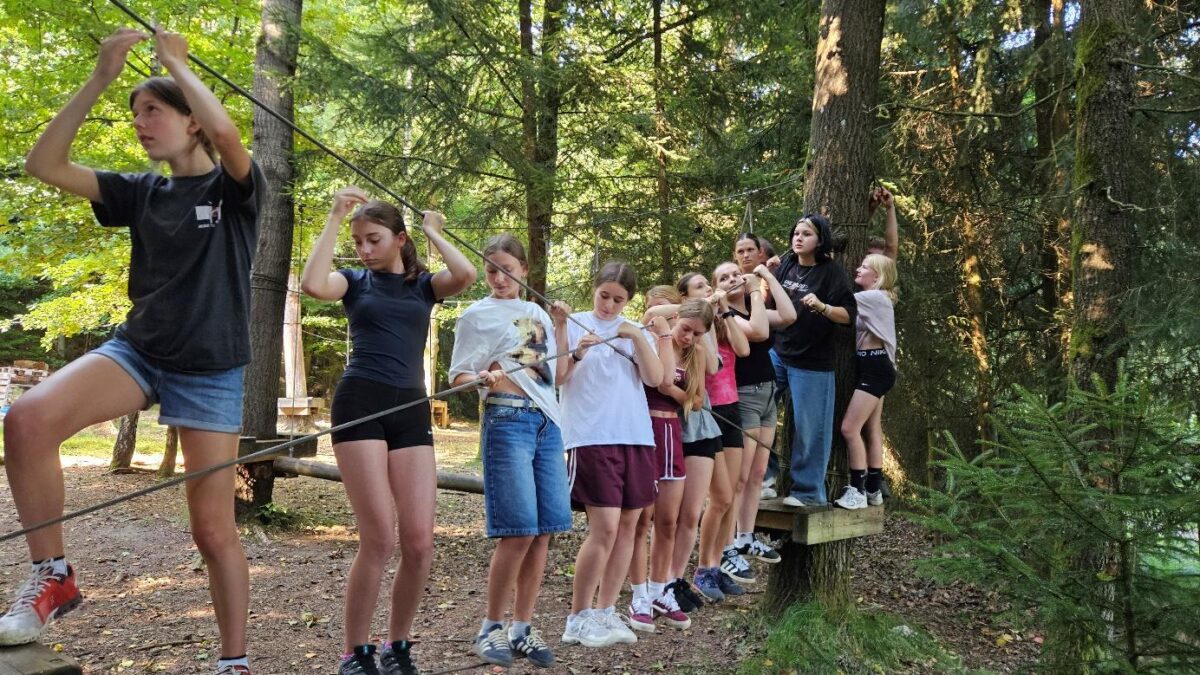 Jugendliche balancieren gemeinsam auf einem Seil im Niedrigseilgarten beim deutsch-tschechischen Sommercamp 2025 in Waldmünchen.