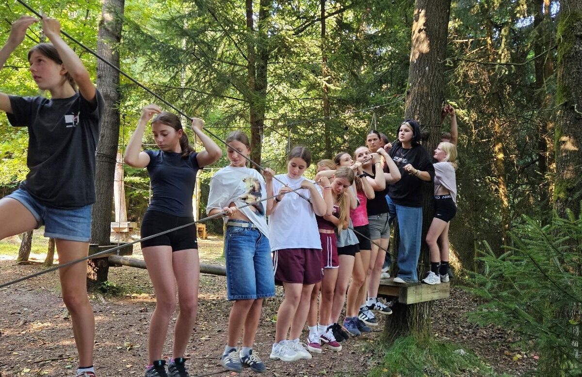 Jugendliche balancieren gemeinsam auf einem Seil im Niedrigseilgarten beim deutsch-tschechischen Sommercamp 2025 in Waldmünchen.