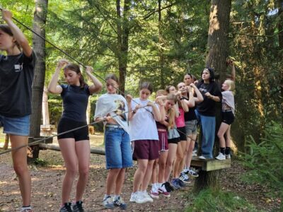 Jugendliche balancieren gemeinsam auf einem Seil im Niedrigseilgarten beim deutsch-tschechischen Sommercamp 2025 in Waldmünchen.