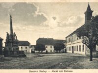 Deutsch Kralupp war eine Kleinstadt in der Nähe von Komotau. Nach dem Zweiten Weltkrieg wurde die deutsche Bevölkerung größtenteils vertrieben. In den 1960er Jahren fiel der Ort dann dem fortschreitenden Braunkohletagebau zum Opfer. Die Dreifaltigkeitssäule, die am Marktplatz stand, steht heute in Zelená, einem Ortsteil von Malkau (Málkov).