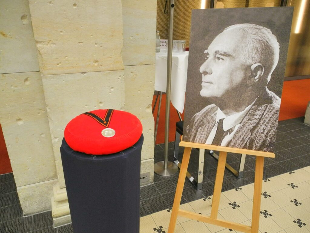 Die neue Johannes-Urzidil-Medaille – benannt nach dem deutsch-tschechischen Schriftsteller und Kulturvermittler – wurde erstmals von der Sudetendeutschen Akademie der Wissenschaften und Künste verliehen. Johannes Urzidil war ein deutschsprachiger Schriftsteller, Dichter, Essayist und Kulturvermittler aus Prag. Geboren am 3. Februar 1896 in einer deutsch-tschechisch-jüdischen Familie, gehörte er zum Kreis um Franz Kafka, Max Brod und Franz Werfel. Nach dem Ersten Weltkrieg arbeitete Urzidil als Journalist und Kulturattaché an der deutschen Gesandtschaft in Prag. 1939 musste er nach der Besetzung Böhmens und Mährens emigrieren – zunächst nach Großbritannien, später in die USA, wo er bis zu seinem Tod 1970 in Rom lebte.