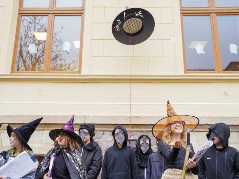 Schülerinnen und Schüler stehen in Kostümen vor dem magischen Hut.