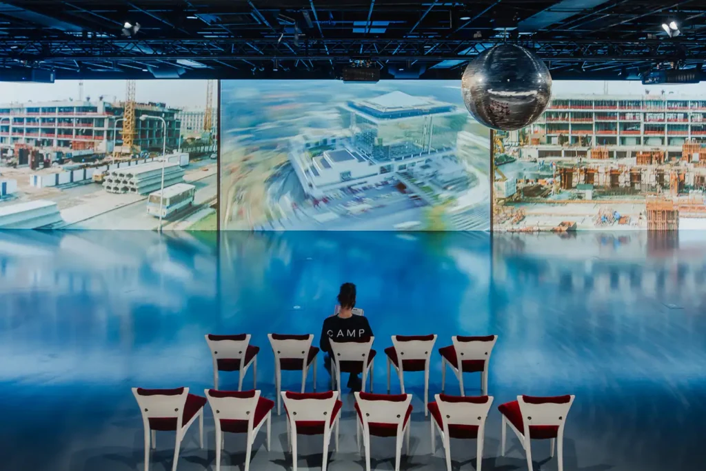 Besucher verfolgen eine Großprojektion mit Archivmaterial und aktuellen Fotografien zum sozialen Kontext der Epoche.