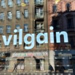 Der weiße Schriftzug scheint grell in den Fenstern des Ladens.