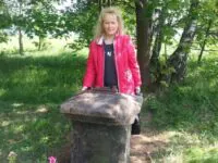Renate von Babka mit dem Gedenkstein ihres Ururopas Karl Beil in der Nähe von Peterswald - Foto: privat