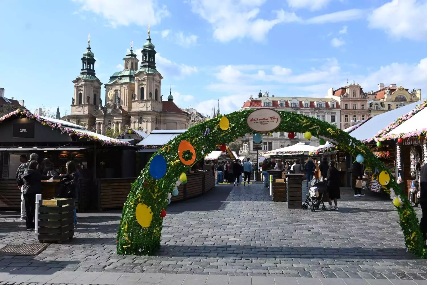 Osterdekoration und Marktstände auf dem Ostermarkt am Altstädter Ring in Prag mit der St.-Nikolaus-Kirche im Hintergrund.